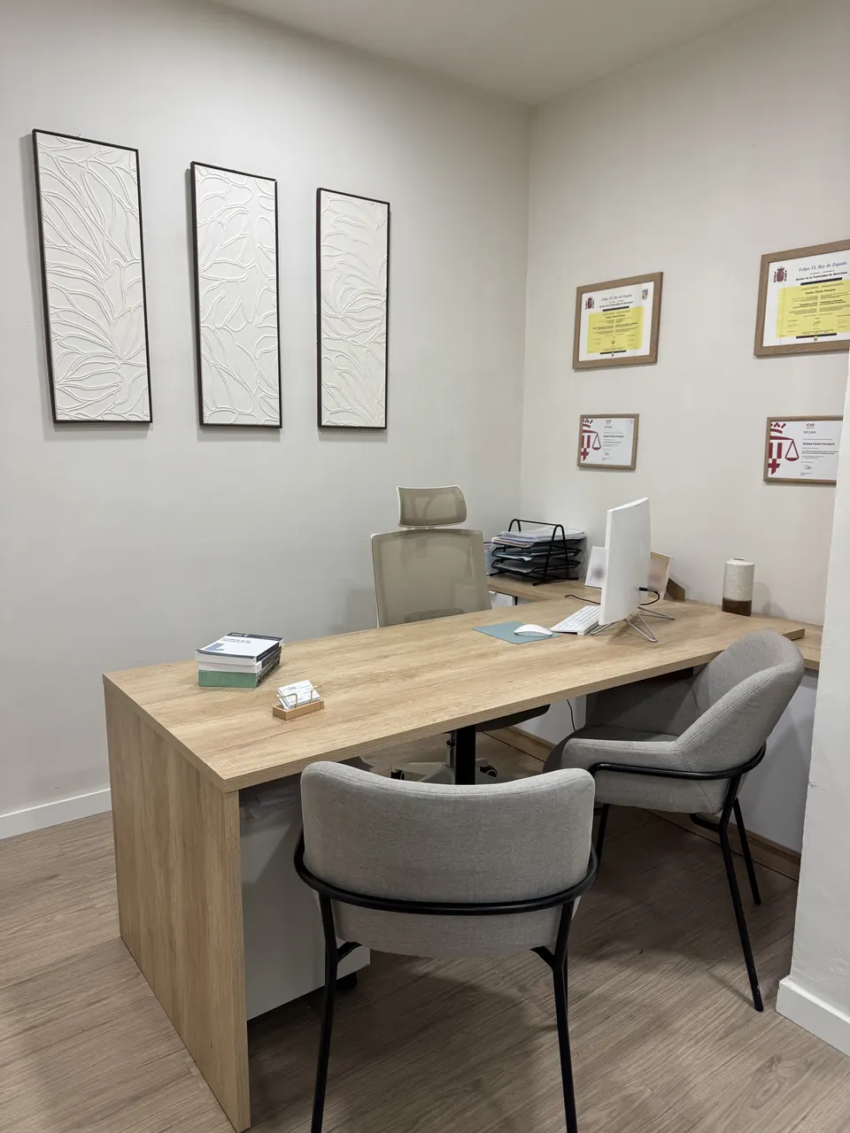 The firm's consultation desk, with two chairs for clients and framed diplomas on the wall